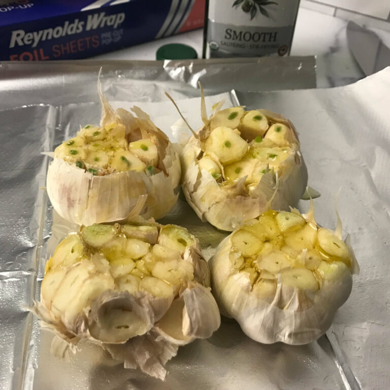 four heads of garlic on a piece of foil.