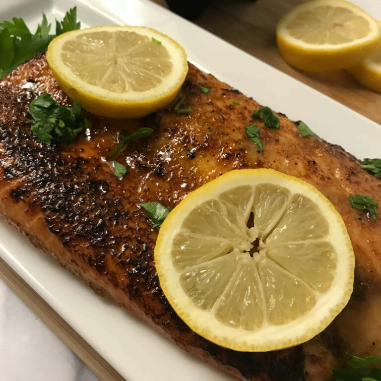 cooked salmon on a platter with lemon wheels.