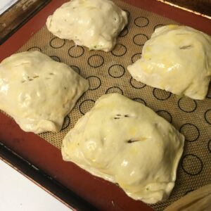 egg washed brushed calzones on a baking sheet.