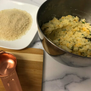 bowl of mixed ingredients next to plate of panko.