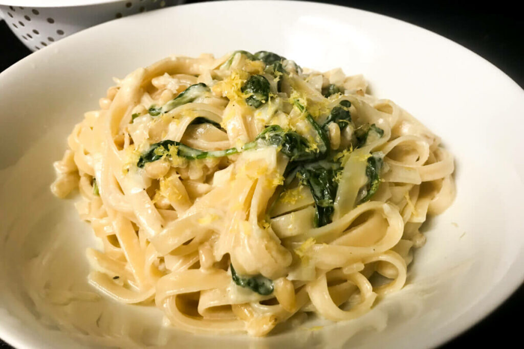 lemon tagliatelle with spinach pinenuts in a bowl.