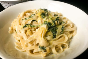 lemon tagliatelle with spinach pinenuts in a bowl.