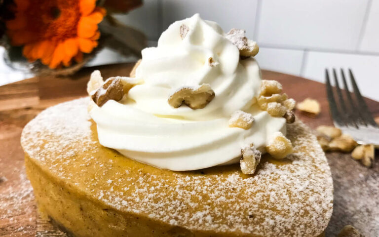 pumpkin cheesecake topped with whipped cream and walnuts.