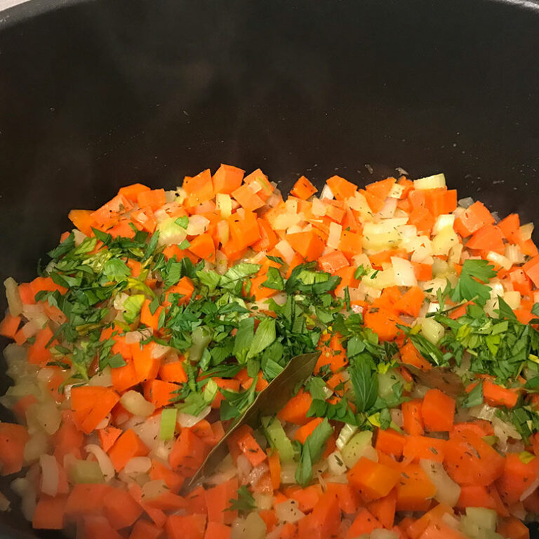 chopped veggies and herbs in a pot.
