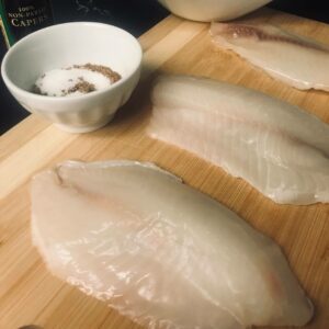 raw tilapia fillets on a board.