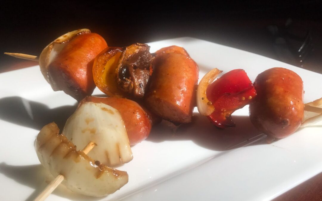 two glazed smoked bratwurst skewers on a plate