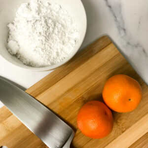 Clementines and powdered sugar on a cutting board.