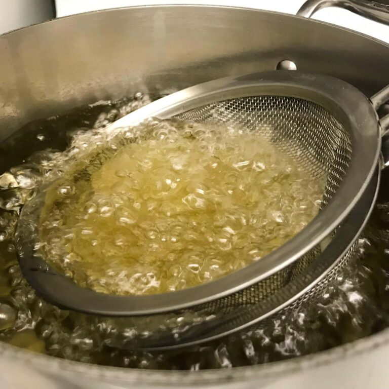 mesh strainer with potatoes boiling in oil.