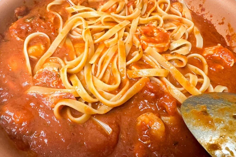 pasta in skillet with sauce and shellfish.