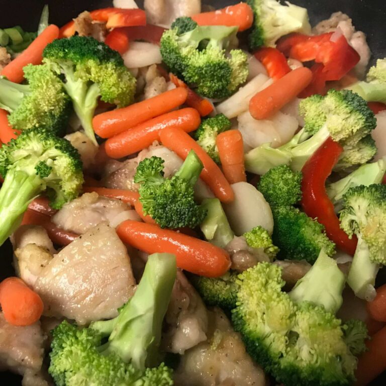 veggies and chicken cooking in skillet.