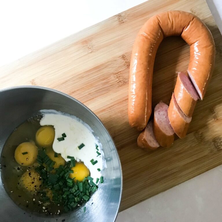 kielbasa next to bowl of eggs and cream.