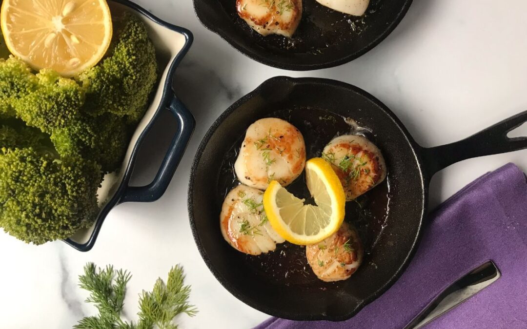 two cast iron skillets with scallops and lemon.