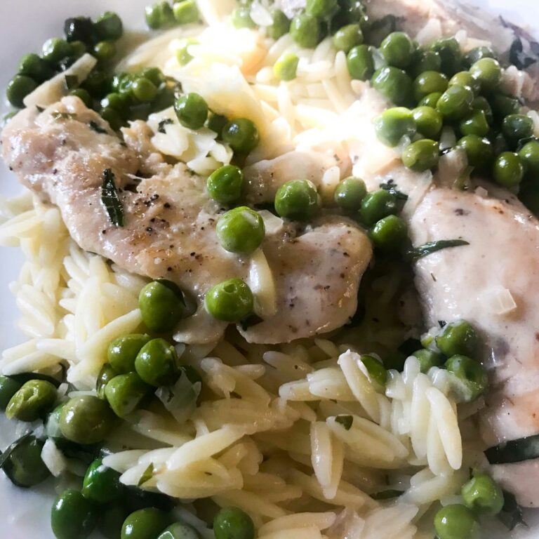 chicken tenders and peas with tarragon cream sauce on a plate with orzo.