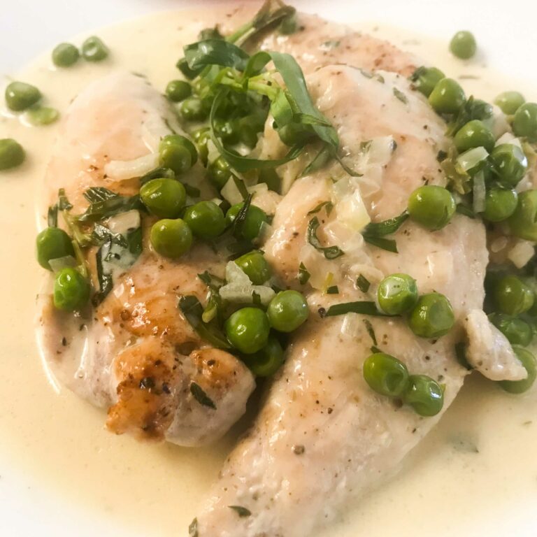 chicken tenders and peas with tarragon cream sauce on a plate.