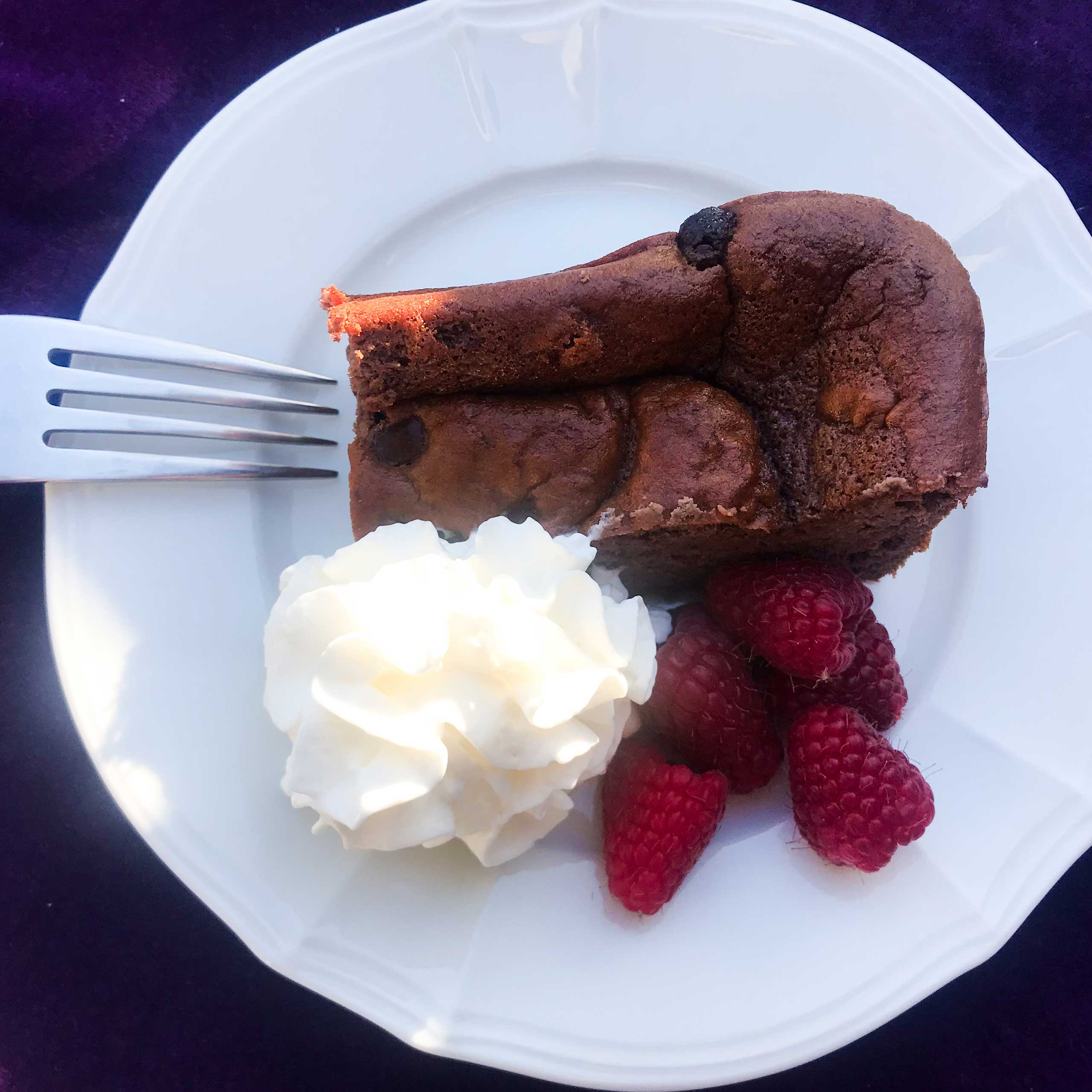 Chocolate protein bar on plate with whipped cream and berries.