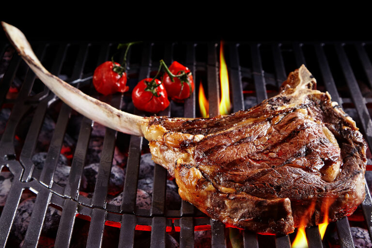 tomahawk steak cooking on a grill.
