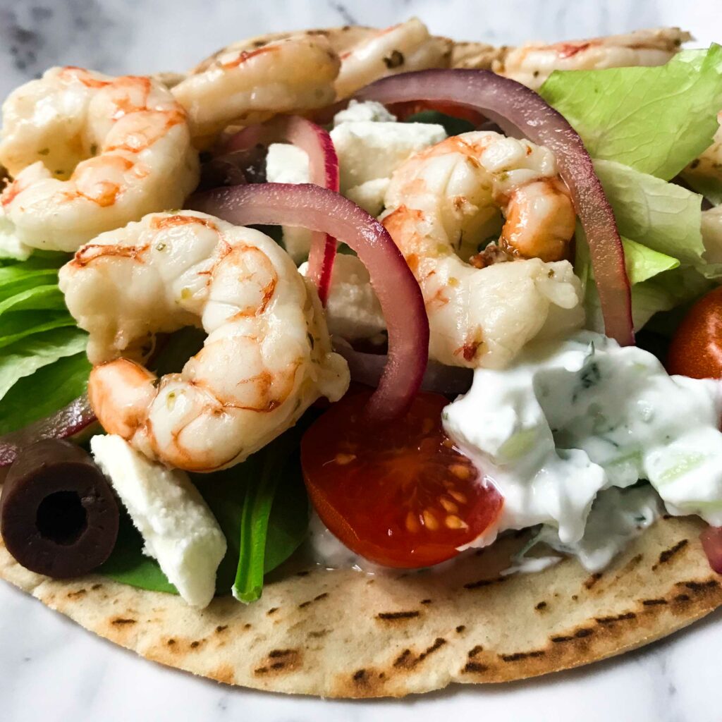 Mediterranean shrimp and tzatziki pita on a plate.