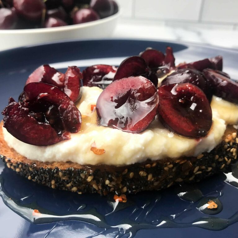 Whipped ricotta toast with cherries and hot honey on a plate.