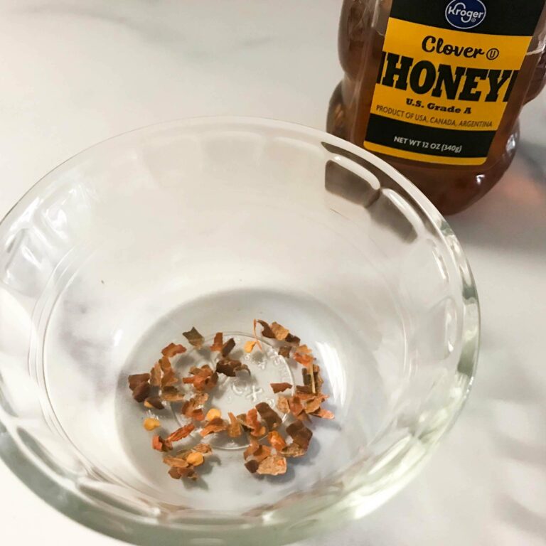 bowl with chili flakes and bottle of honey.