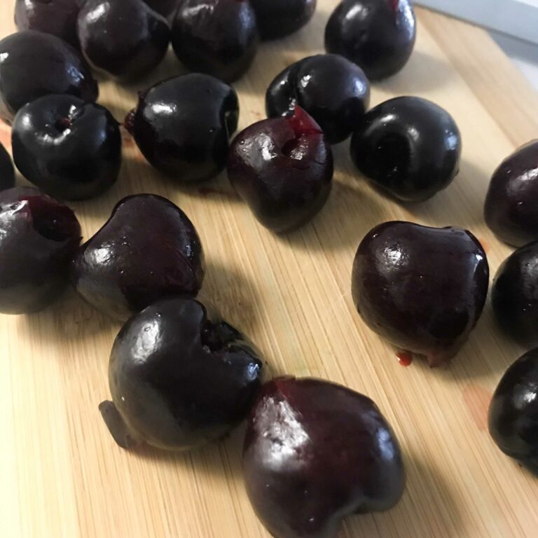 pitted cherries on a cutting board.