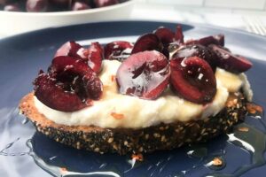 Whipped ricotta toast with cherries and hot honey on a plate.