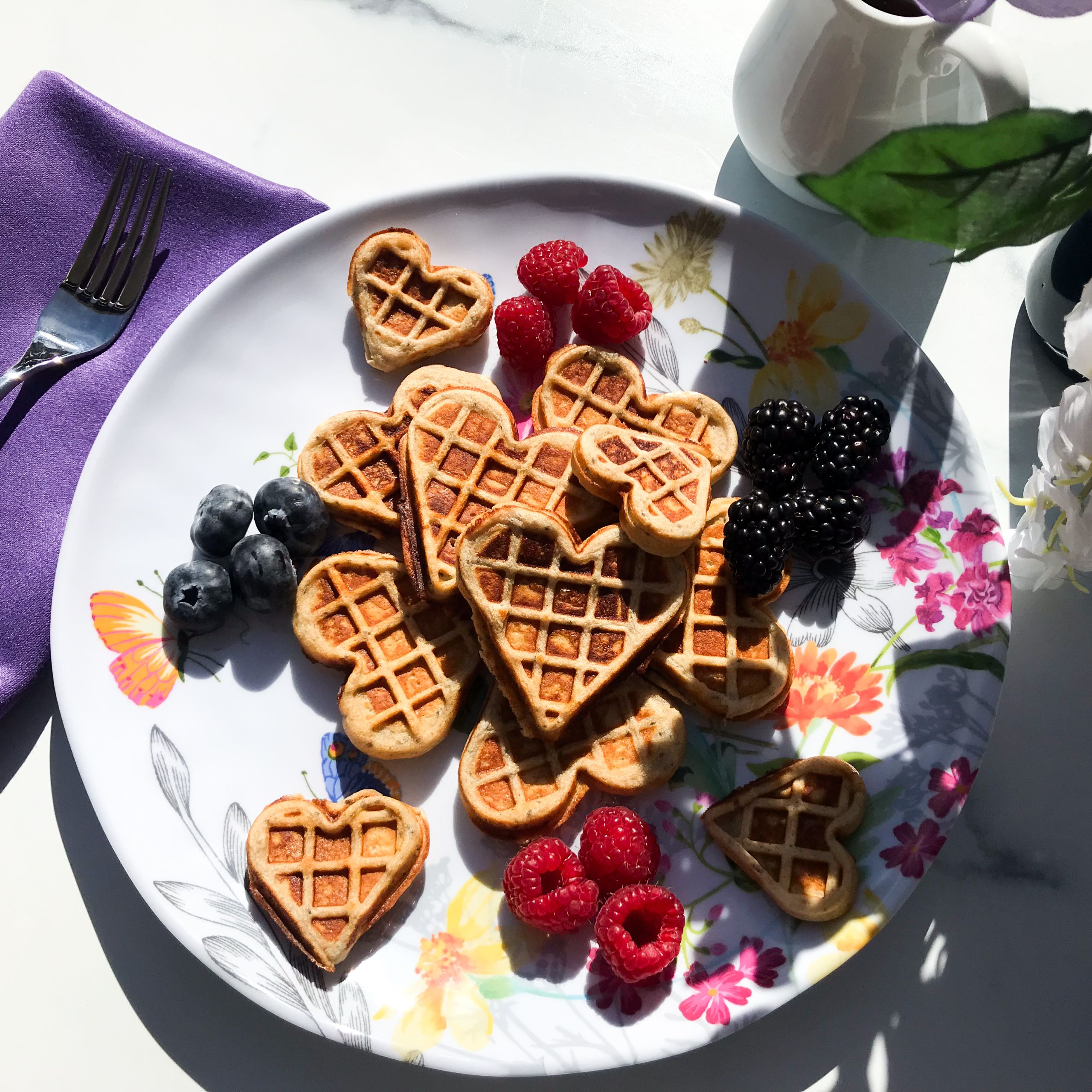 plate of heart shaped waffles with fresh berries.