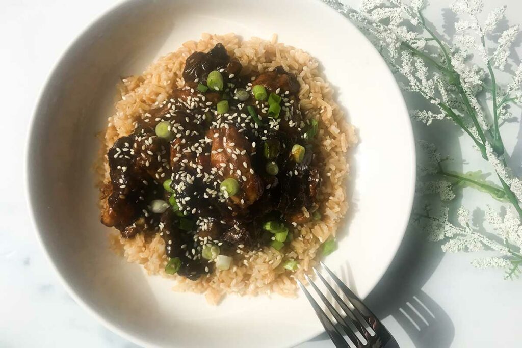 a bowl of healthy bourbon chicken over brown rice.