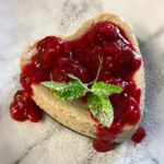 cheesecake topped with raspberry sauce and mint leaf.