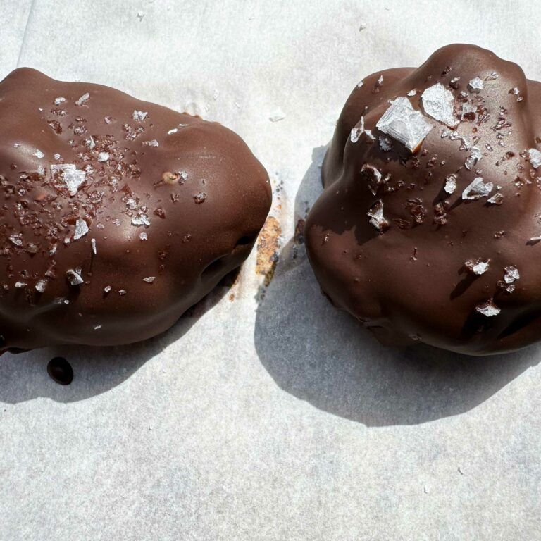 two chocolate dipped yogurt bites on a baking sheet.