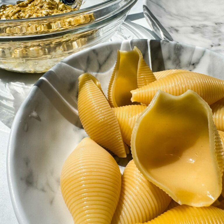 cooked pasta shells in a bowl next to bowl of filling.