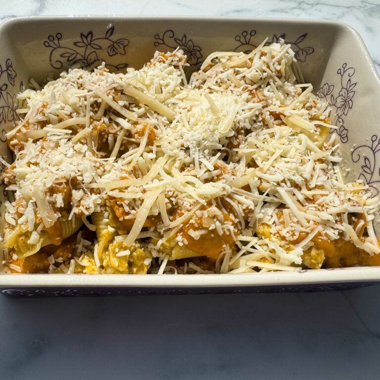 pasta shells in casserole dish topped with cheese.
