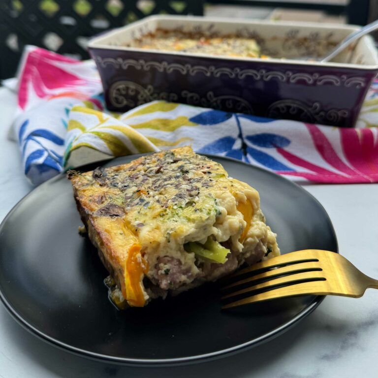 wedge of egg, veggie, ham and cheese casserole on a plate with fork.