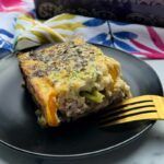 a square of egg, veggie, ham and cheese casserole on a plate.