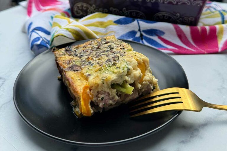 a square of egg, veggie, ham and cheese casserole on a plate.