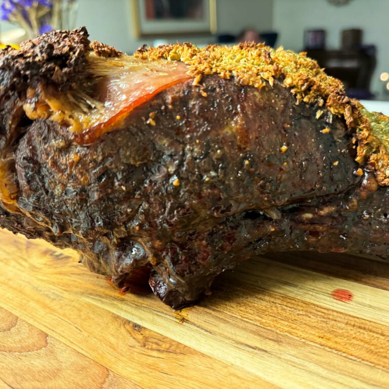 cooked rib roast sitting on a cutting board.