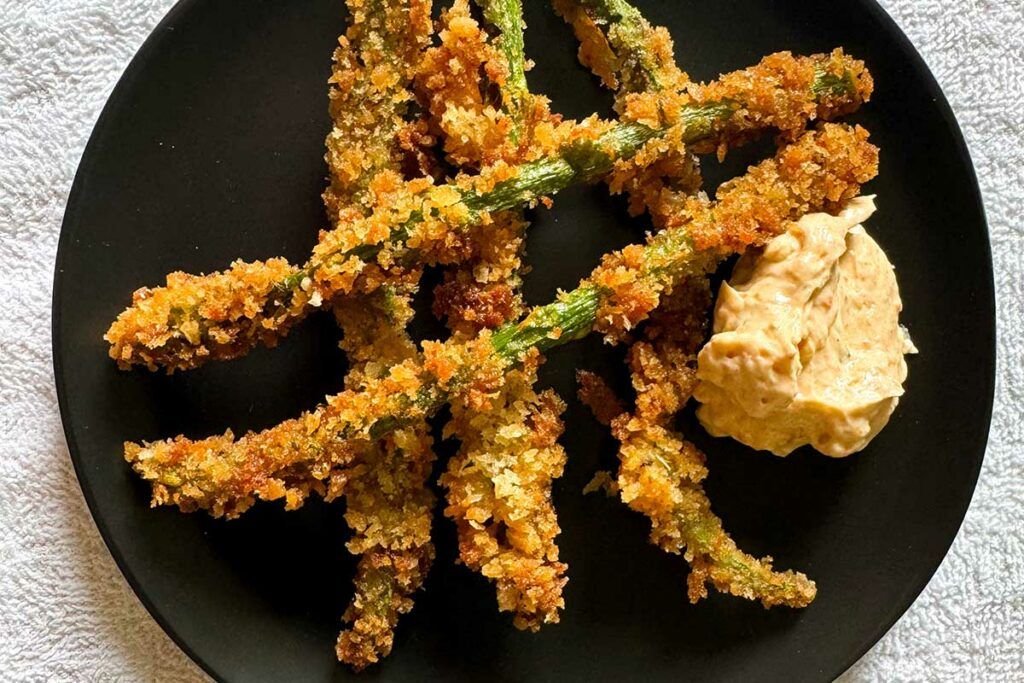 Crispy Parmesan Asparagus with Parmesan Dipping sauce on a plate.