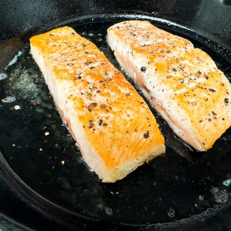 salmon fillets cooking in a skillet.