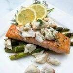 Salmon Oscar on a plate with lemon wheels.