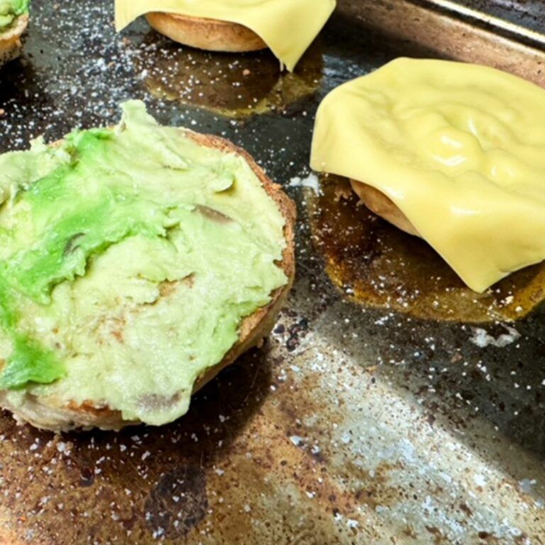 toasted bagel with cheese and avocado schmeared on top.