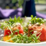 compressed watermelon Feta & Arugula salad with jalapeno dressing on a plate.