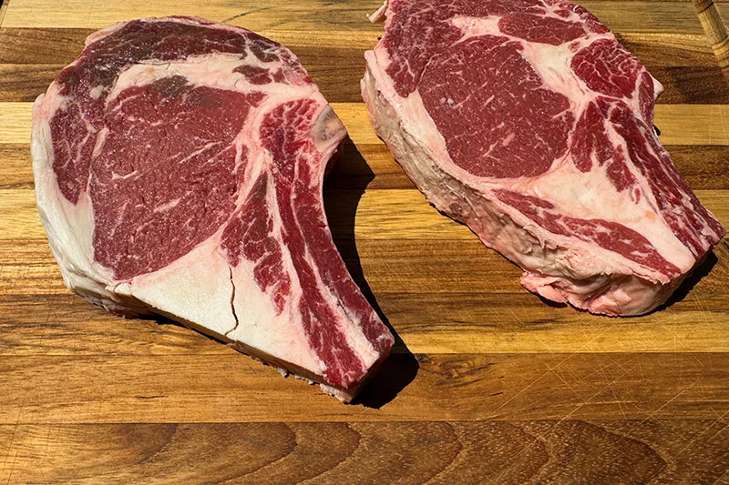 raw rib eye steaks on cutting board.