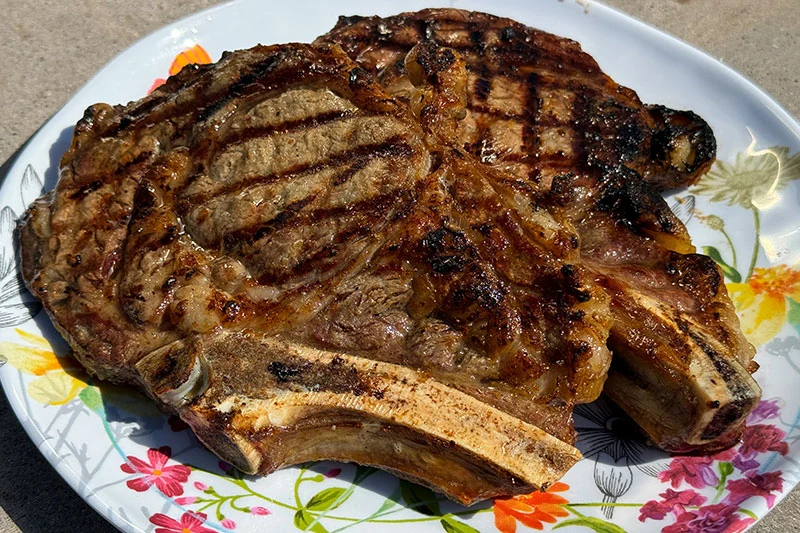 cooked rib eye steaks on a platter.