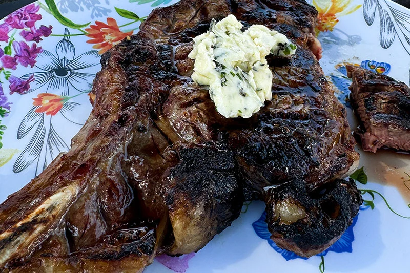 cooked rib eye steaks on a platter with her butter.