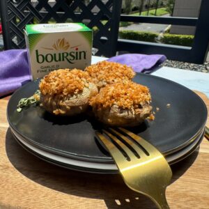 boursin stuffed mushrooms on a plate with a box of the cheese.