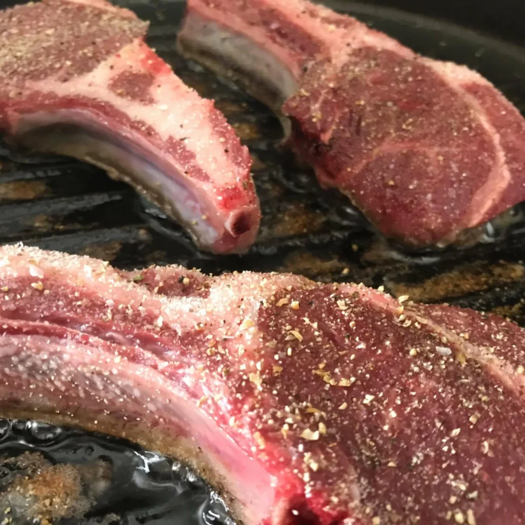 raw, marinated lamb chops on the grill.