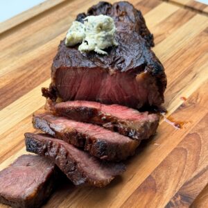cooked and sliced steak with herb butter.