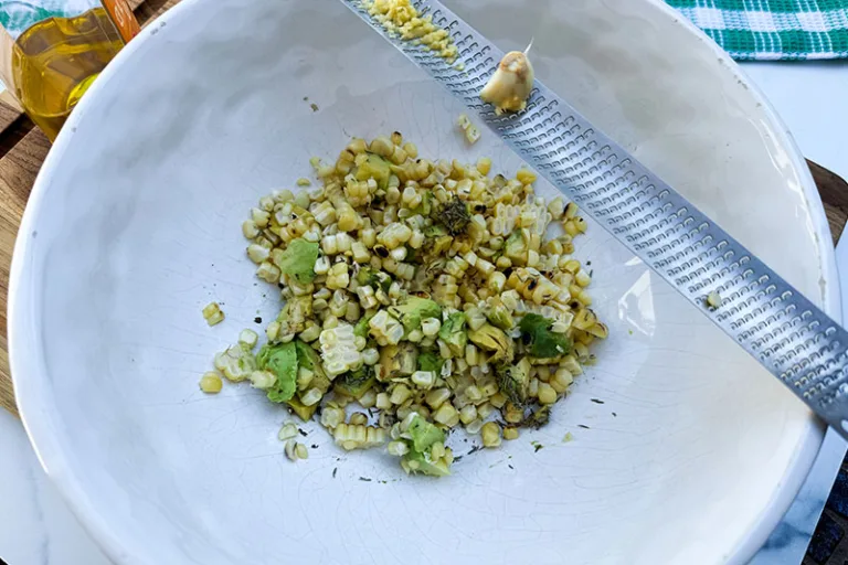 ingredients in a bowl with garlic grater.