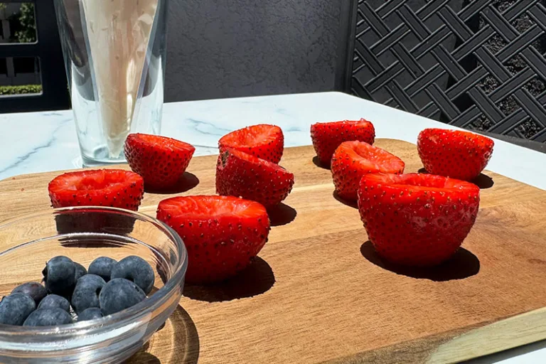 cut and hulled strawberries and bowl of blueberries.