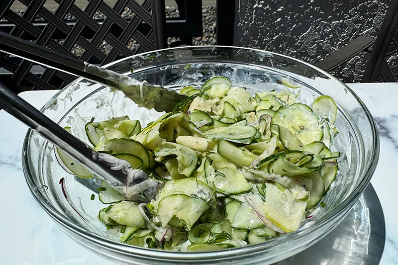 salad tossed with dressing in a bowl.