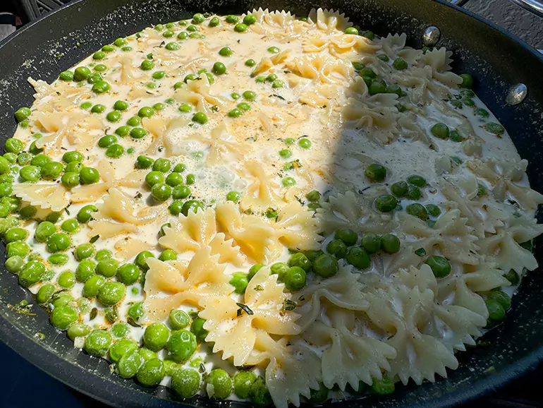 pasta and peas cooking in cream sauce.